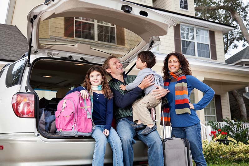 Happy family at their car outside their home